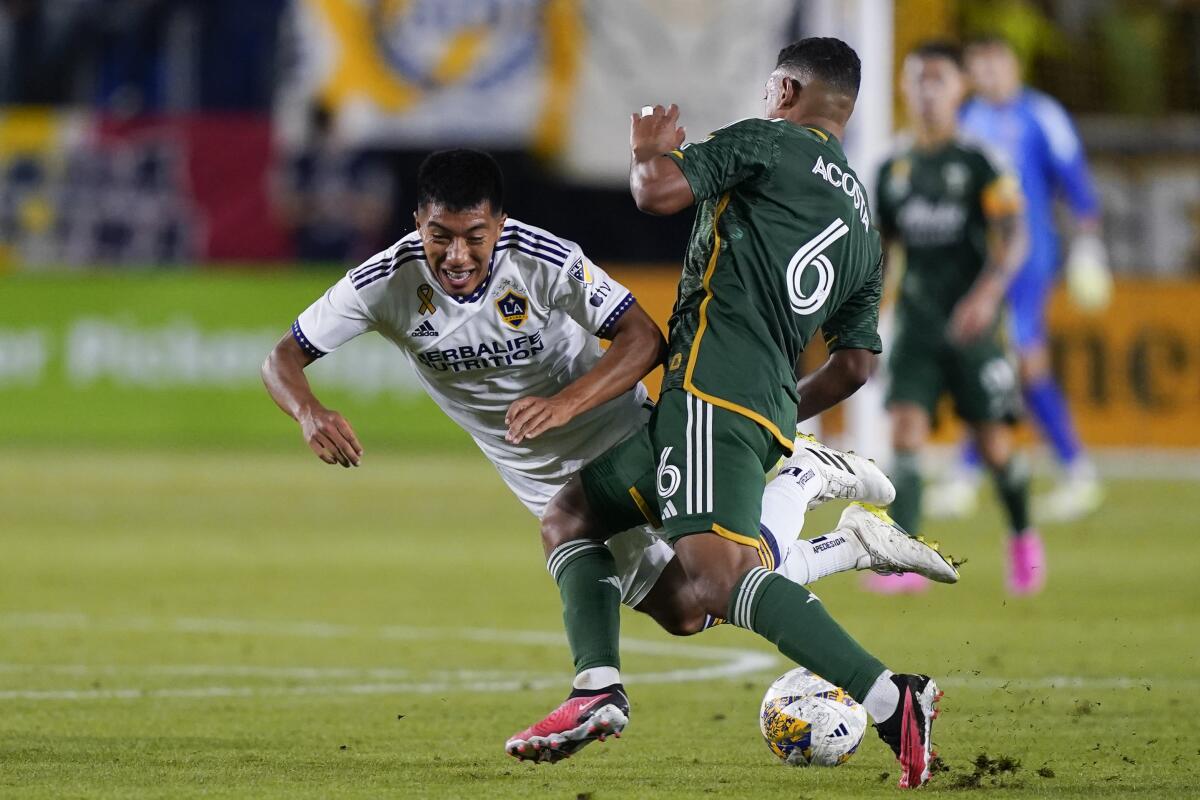 Galaxy midfielder Daniel Aguirre, left, collides with Portland Timbers midfielder Bryan Acosta.