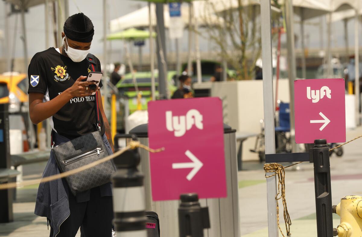 A person standing near Lyft signs looks at a phone. 