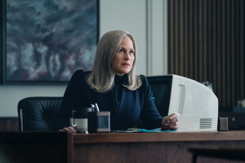 A woman sits at a desk next to a computer