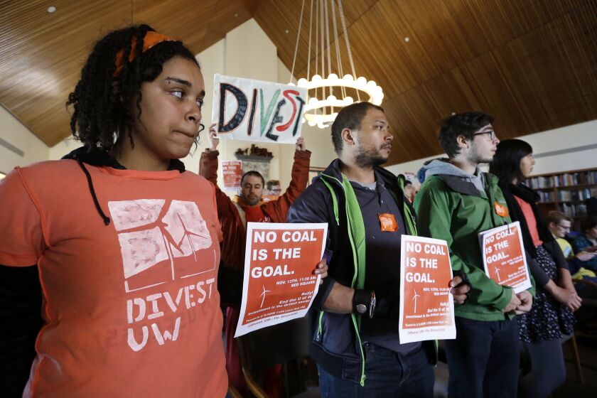 University of Washington senior Sarra Tekola, left, stands with other protesters at a Board of Regents meeting Thursday, Nov. 13, 2014, in Seattle. Members of the student group Confronting Climate Change spoke at the meeting, asking the school to divest itself from direct holdings in oil sands and coal. (AP Photo/Elaine Thompson)