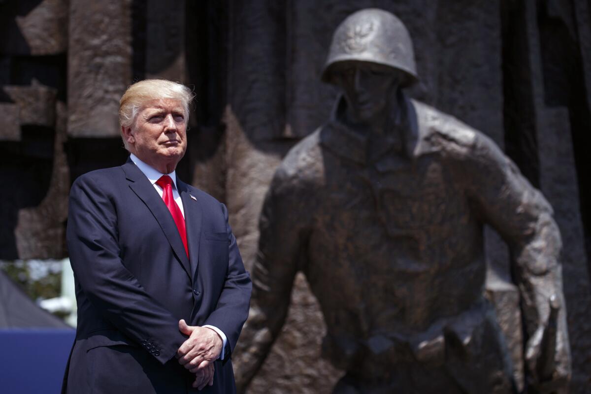 President Donald Trump listens as he is introduced to deliver a speech at Krasinski Square in Warsaw on July 6, 2017. Behind him is a memorial to the 1944 Warsaw Uprising against Poland's Nazi occupiers.