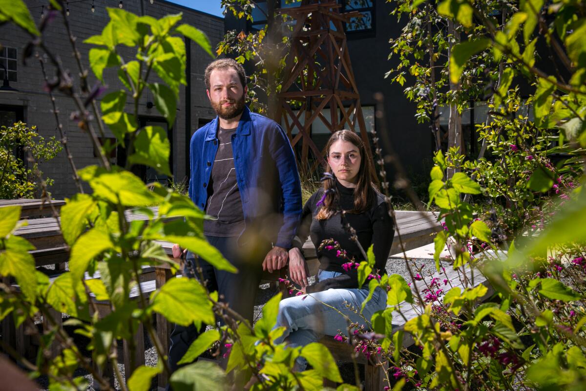 A man and a woman pose in a garden.