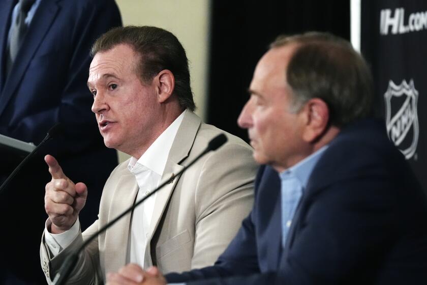 Arizona Coyotes Chairman and Governor Alex Meruelo, left, speaks as NHL Commissioner Gary Bettman, right, listens as they hold a news conference regarding a provision for Arizona to get an expansion team if a new arena is built within the next five years with the announcement of the current team relocating to Salt Lake City, Friday, April 19, 2024, in Phoenix. The Coyotes are officially headed to Salt Lake City after NHL Board of Governors voted Thursday to approve a $1.2 billion sale from Meruelo to Utah Jazz owner Ryan Smith, with Meruelo retaining the Coyotes' name, logo and trademark. (AP Photo/Ross D. Franklin)