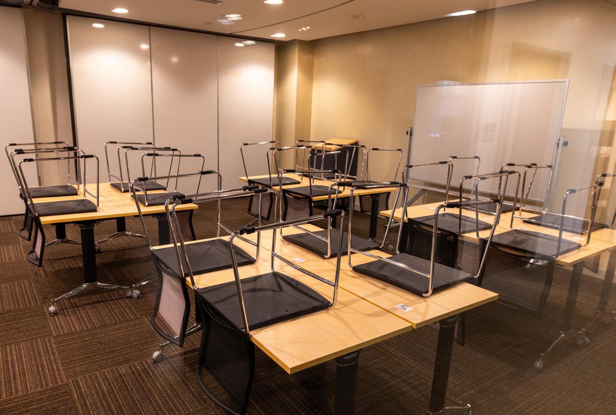 An empty classroom with chairs on desks at the Academy of Media Arts.