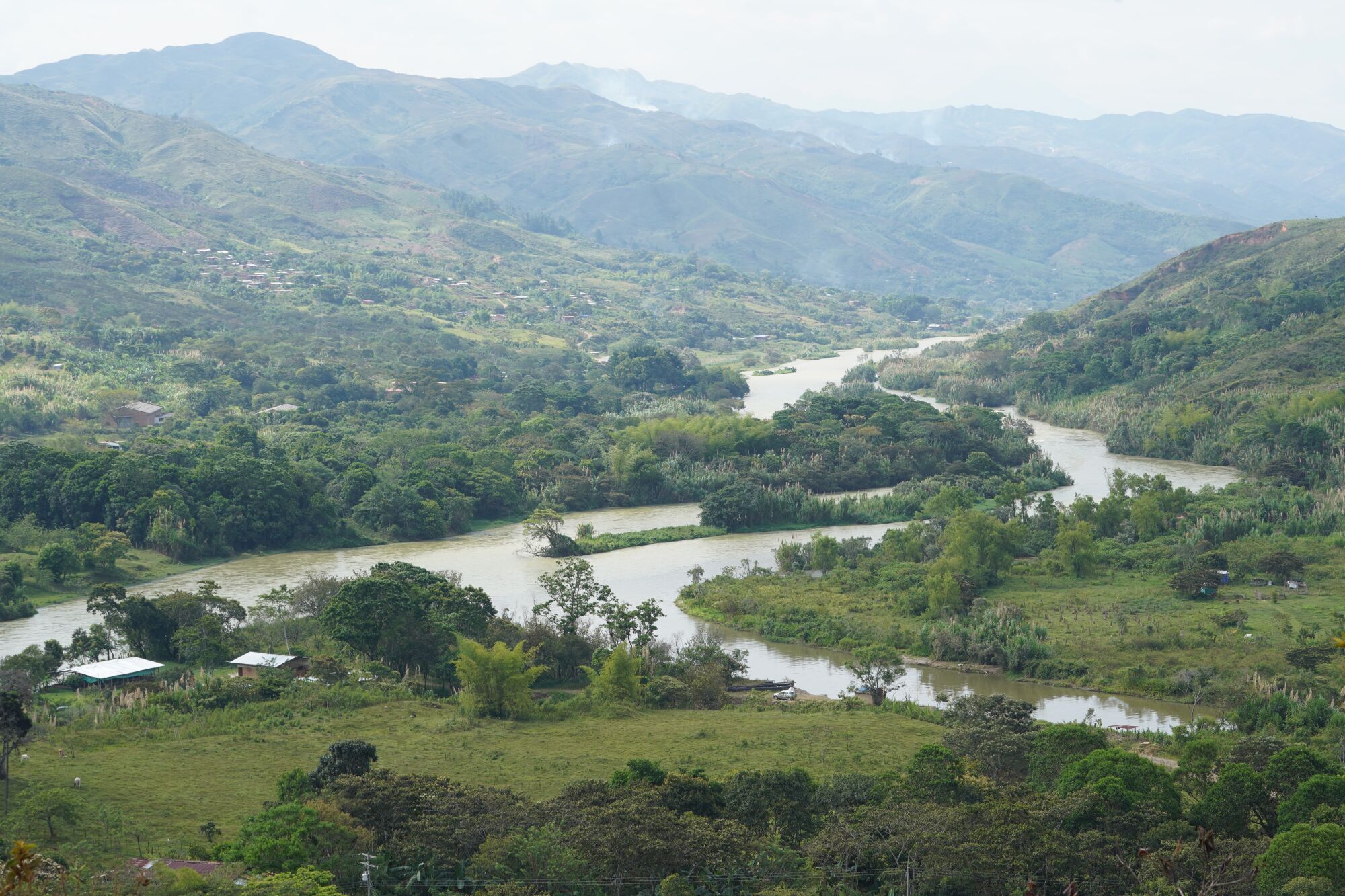 A view of La Toma, Colombia, includes waterways and green hills under an overcast sky