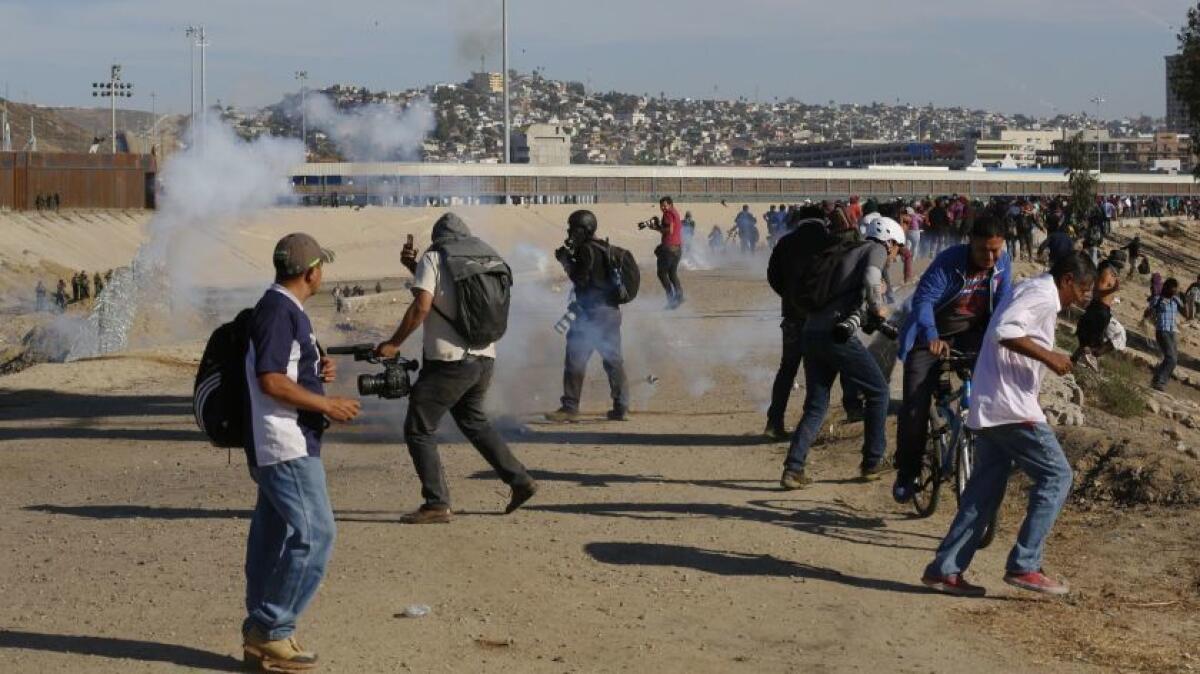 En esta foto de archivo del 25 de noviembre de 2018, un migrante huye de gases lacrimógenos lanzados por agentes de Estados Unidos, en medio de miembros de la prensa que cubren la frontera de EE.UU y México, después de que un grupo de migrantes superara a la policía mexicana en el cruce del Chaparral en Tijuana, México.