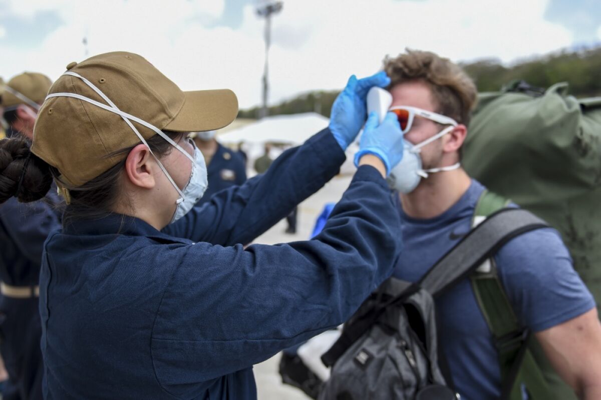 Sailors assigned to USS Theodore Roosevelt who have tested negative twice for COVID-19 and are asymptomatic arrive pierside, preparing to return to the ship after off-ship quarantine on April 30.