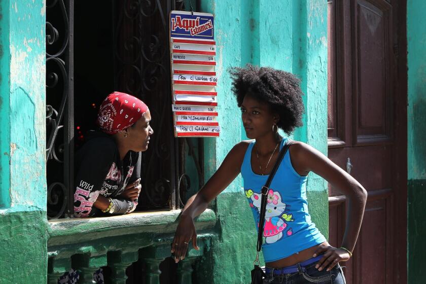 Two women chat at a window of a cafe in Havana, Cuba.