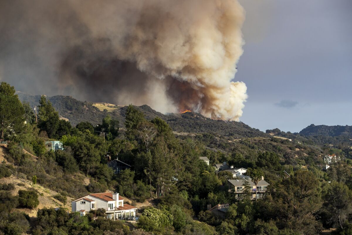 The Palisades wildfire burns out of control in rugged terrain near homes above Topanga Canyon Boulevard.