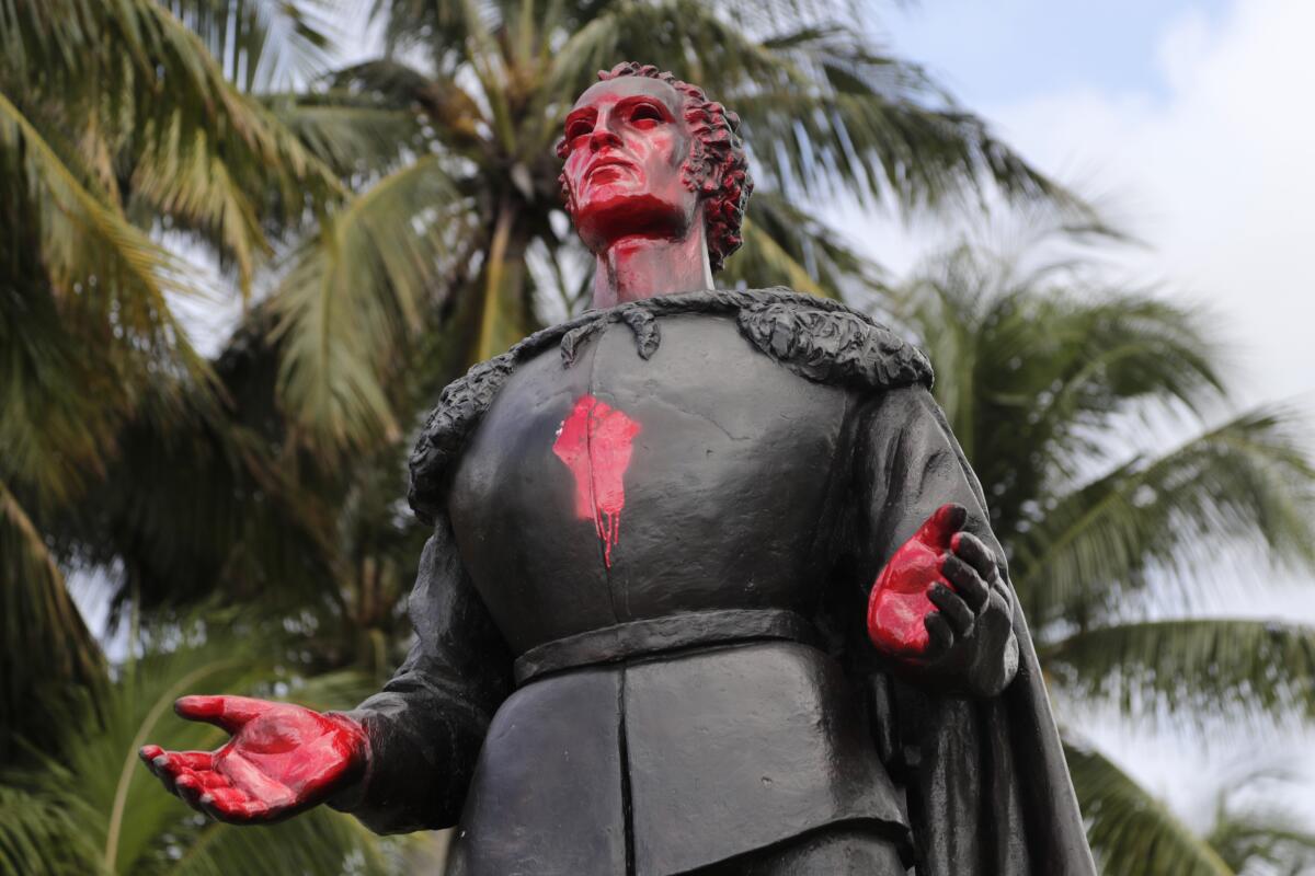 A statue of Christopher Columbus with his face and hands spray-painted red