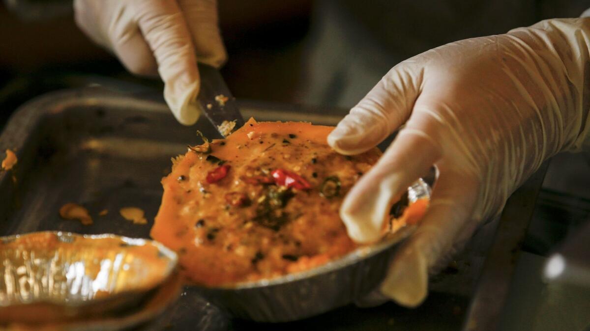 It resembles a mini-quiche with bits of pork, fish and mushrooms, and Hue Phan scoops the "mam chung" from its containers, ready for a taste. (Mark Boster / Los Angeles Times)