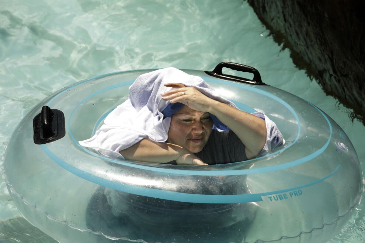 A woman puts a towel on her head while in a pool.