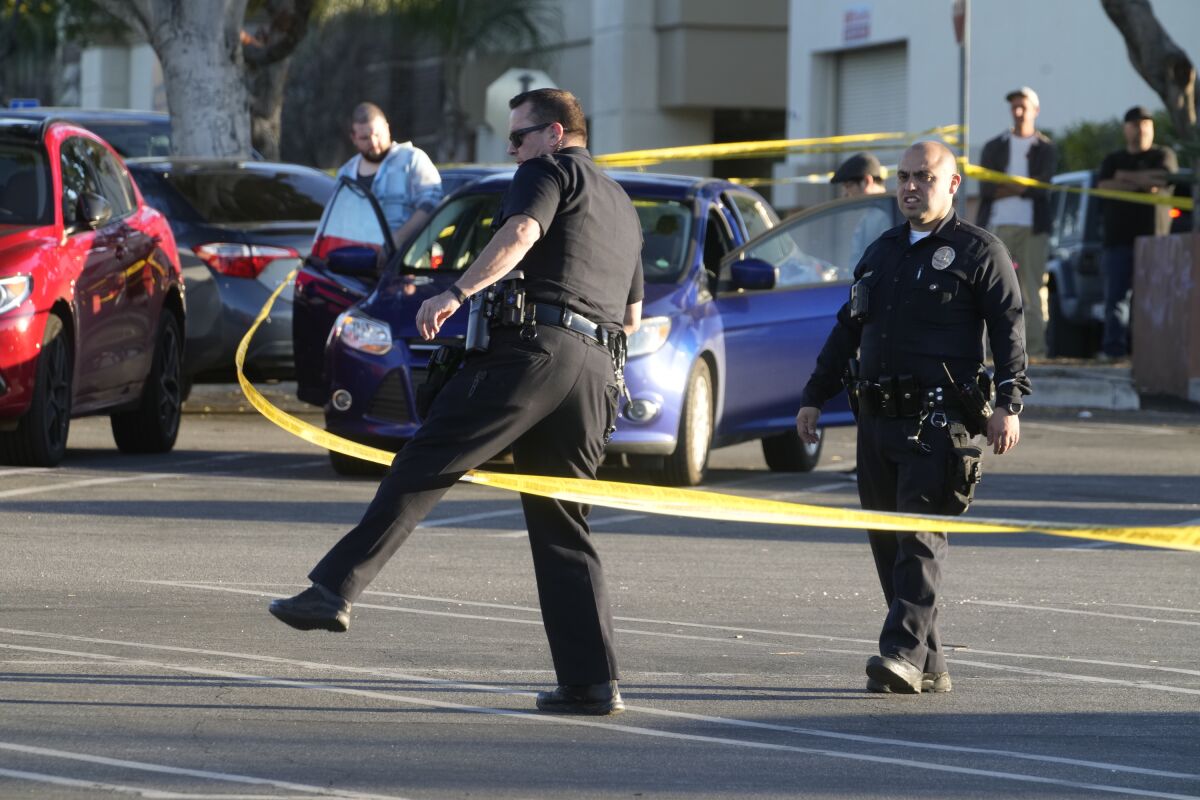 Los Angeles police investigate the scene of a fatal shooting in a shopping mall parking lot in Los Angeles, Saturday, April 1, 2023. (AP Photo/Damian Dovarganes)