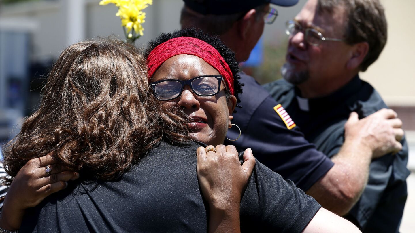 Mourners hug after praying in front of the roadside memorial for the three slain police officers on Airline Highway in Baton Rouge, La.
