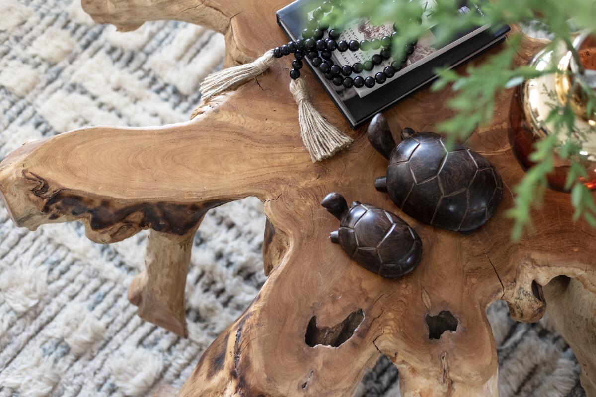 A live-edge coffee table in the Encinitas living room is topped with carvings and plants.
