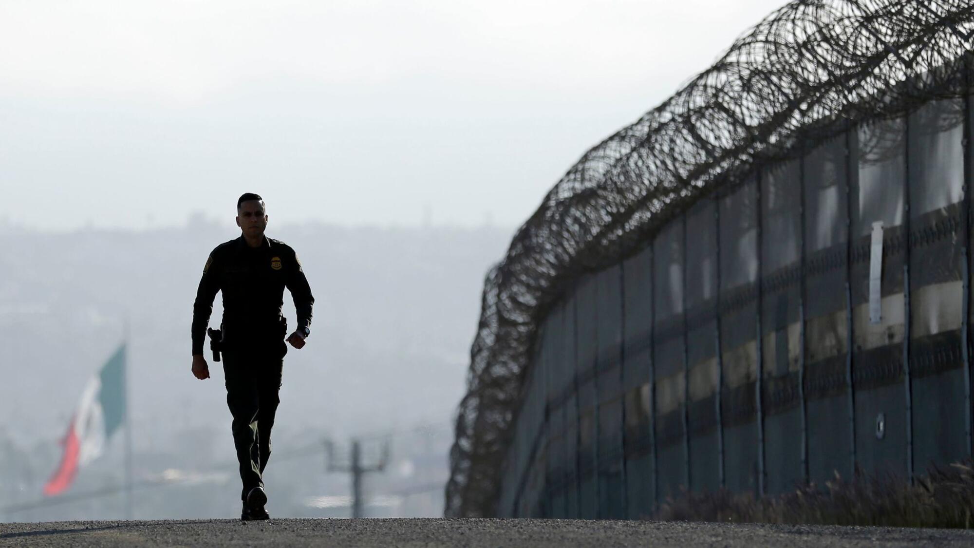 A Border Patrol agent walks near the secondary fence separating Tijuana, Mexico, and San Diego.