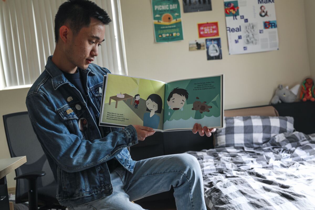 Jeremy Dang, in his bedroom with a children's book he wrote and illustrated
