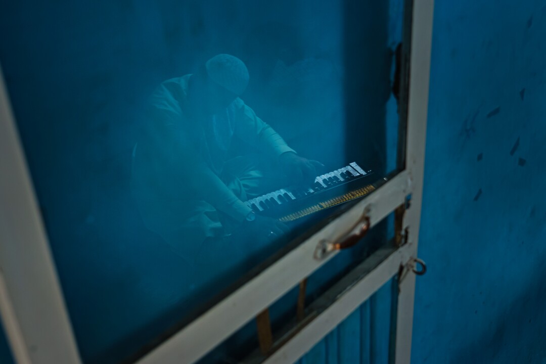 Ramin Saqizada, a rubab player practices on an accordion-like instrument in his workshop.