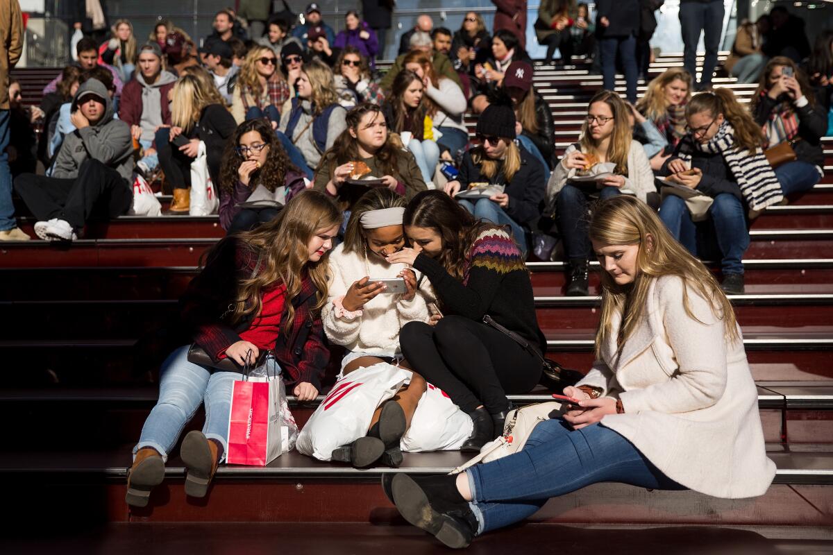 Some teens look at a photograph they took on a smartphone in Times Square in New York City.
