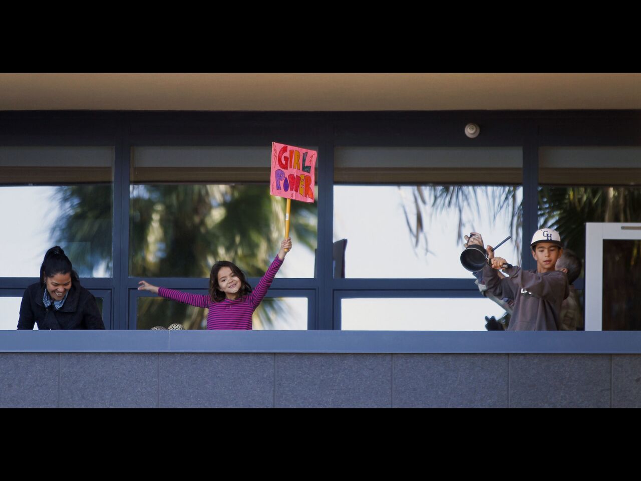 Children cheer on the marchers from a balcony on Pacific Highway.