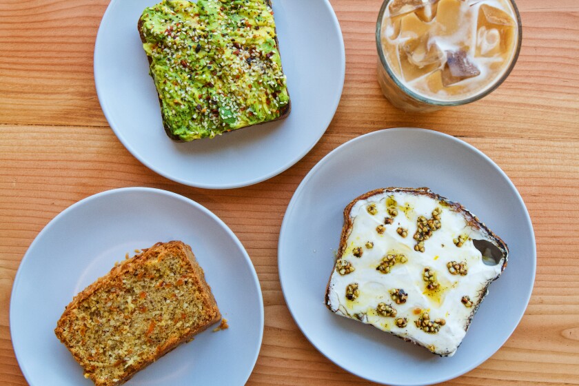 Overheadshot of three light blue plates each with a slice of a bread, and a coffee drink