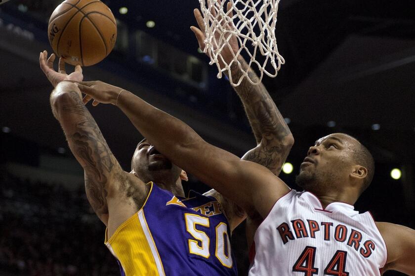 Raptors forward Chuck Hayes blocks the shot of Lakers center Robert Sacre in the first half of a 2014 game.