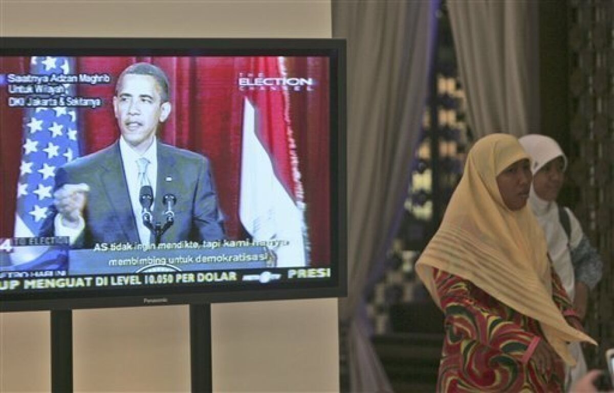Indonesian Muslim women walk past by a TV screen showing President Barack Obama delivering his speech at a shopping mall in Jakarta, Indonesia, Thursday, June 4, 2009. (AP Photo/Tatan Syuflana)