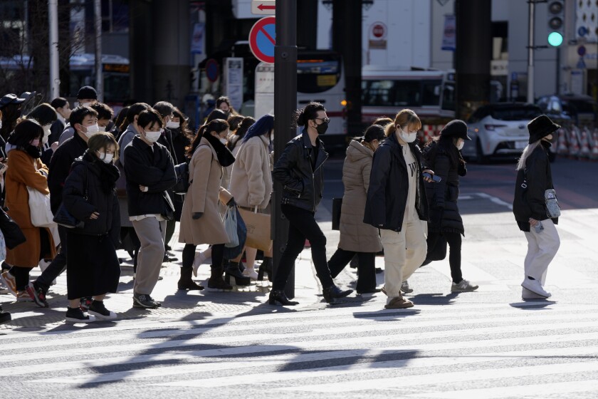 Unas personas portan mascarillas para frenar la propagación del coronavirus en un cruce peatonal el viernes 21 de enero de 2022, en Tokio. (AP Foto/Eugene Hoshiko)