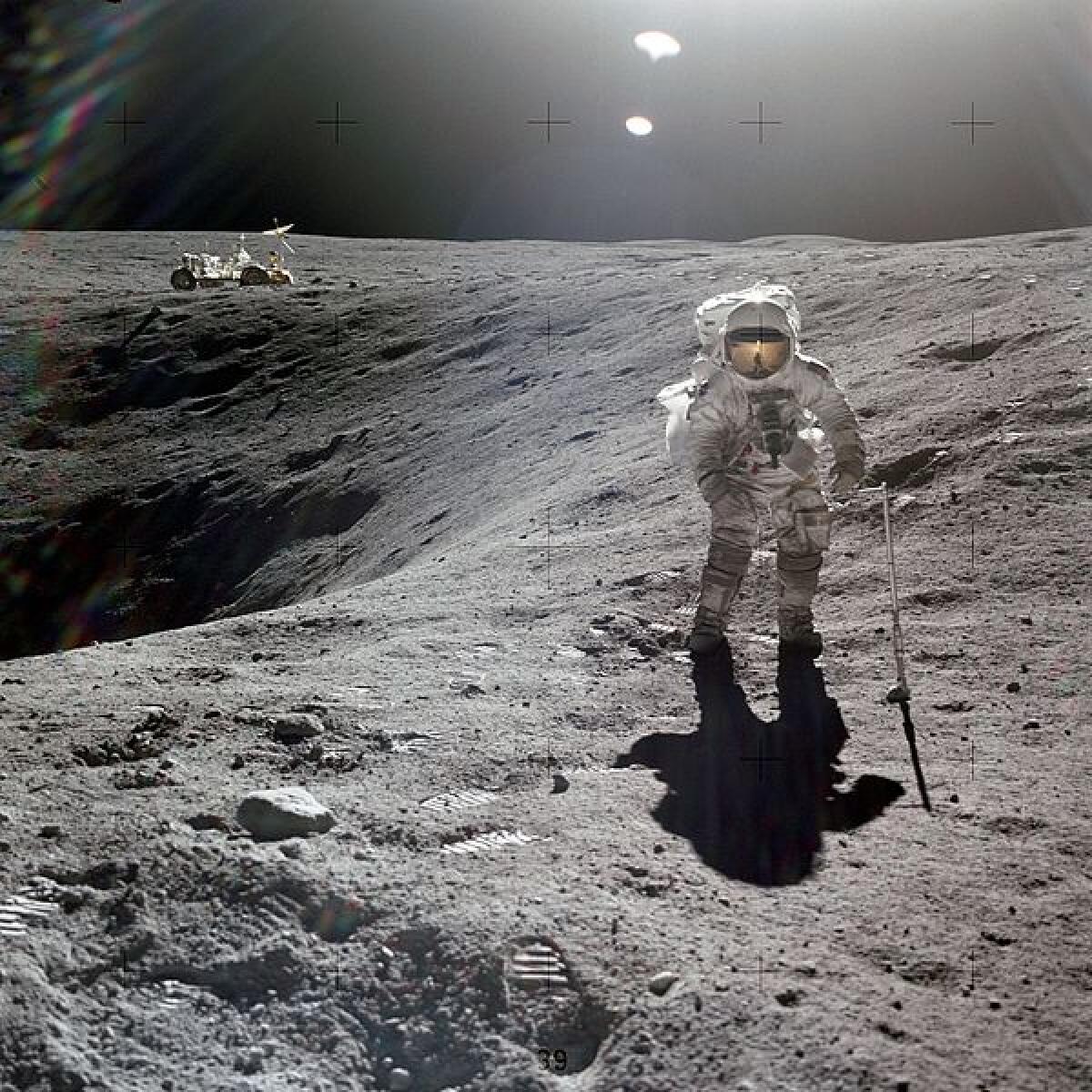 An astronaut walks on the moon with a lunar rover in the background.