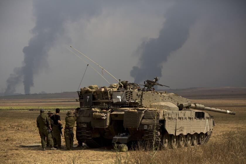Israeli soldiers stand behind a tank as heavy smoke rises from the Gaza Strip on July 22.