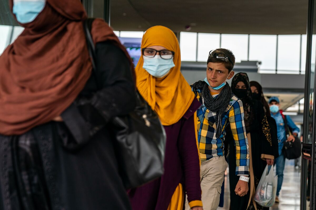 A line of refugees, some wearing face masks 