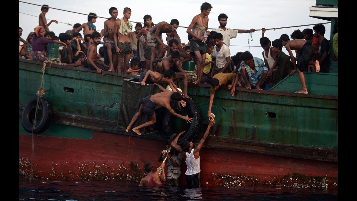 Rohingya migrants pass food supplies dropped by a Thai army helicopter to others aboard a boat drifting in Thai waters off the southern island of Koh Lipe in the Andaman Sea on May 14, 2015. A boat crammed with scores of Rohingya migrants - including many young children - was found drifting in Thai waters on May 14, with passengers saying several people had died over the last few days.