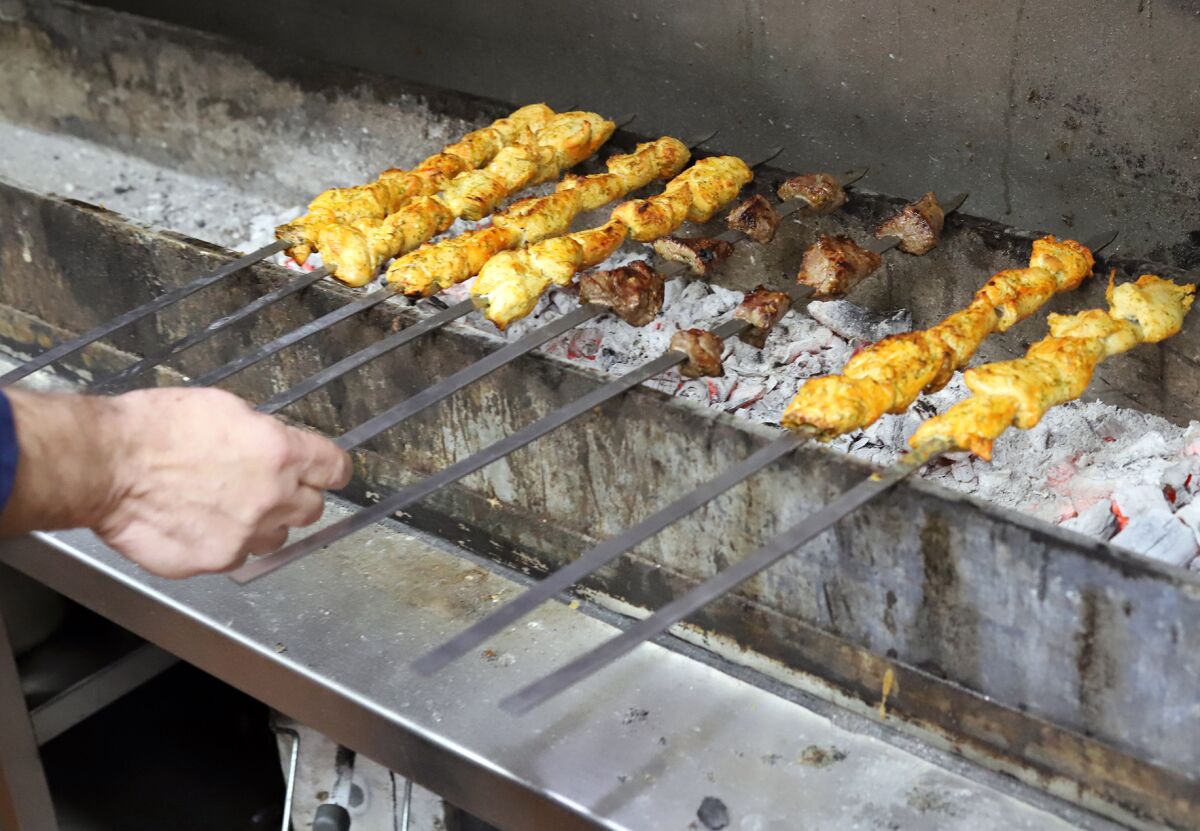Sam Nordin, the owner of the Desert Moon Grill, grills over hot coals.