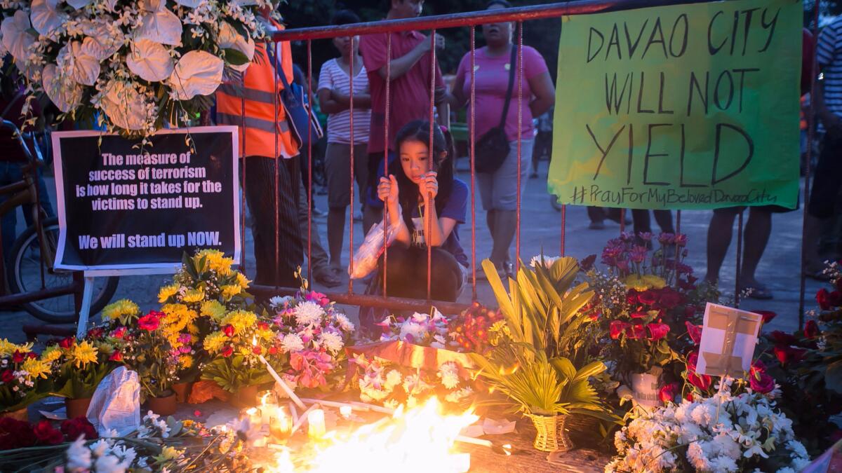 A young resident looks at lighted candles and flowers at a memorial for bomb blast victims in Davao City, on the southern Philippine island of Mindanao on Sept. 3, 2016.