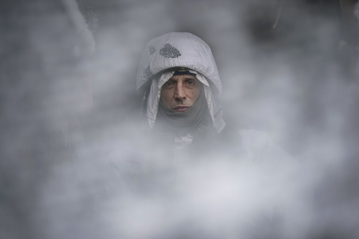 A Ukrainian serviceman, seen through a camouflage mesh, stands at a frontline position in the Luhansk region, eastern Ukraine, Saturday, Jan. 29, 2022. (AP Photo/Vadim Ghirda)
