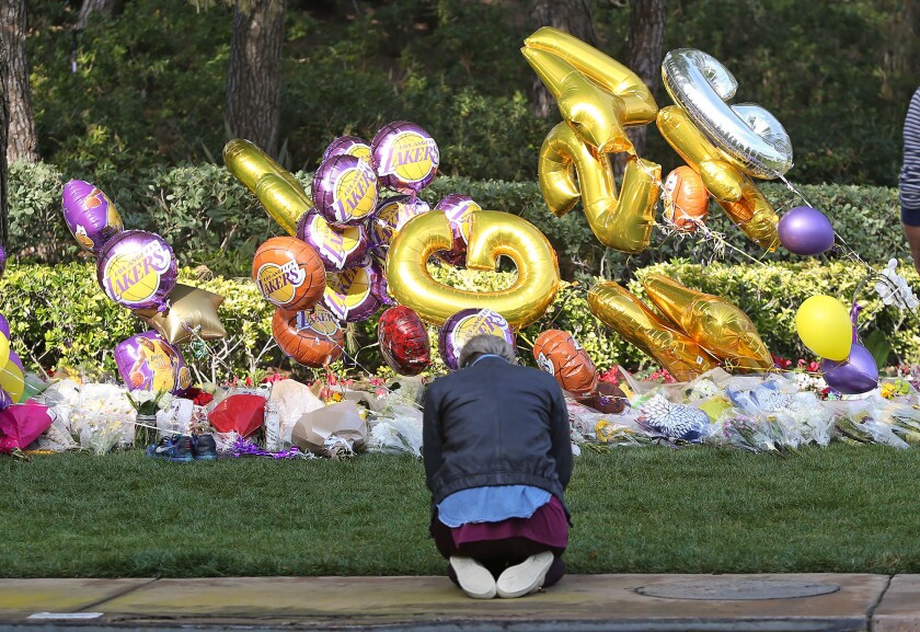 A woman prays Monday at a makeshift memorial for Lakers legend Kobe Bryant.