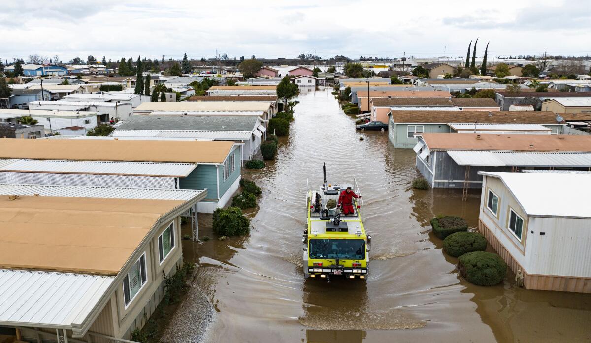 An emergency vehicle drives along a flooded street.
