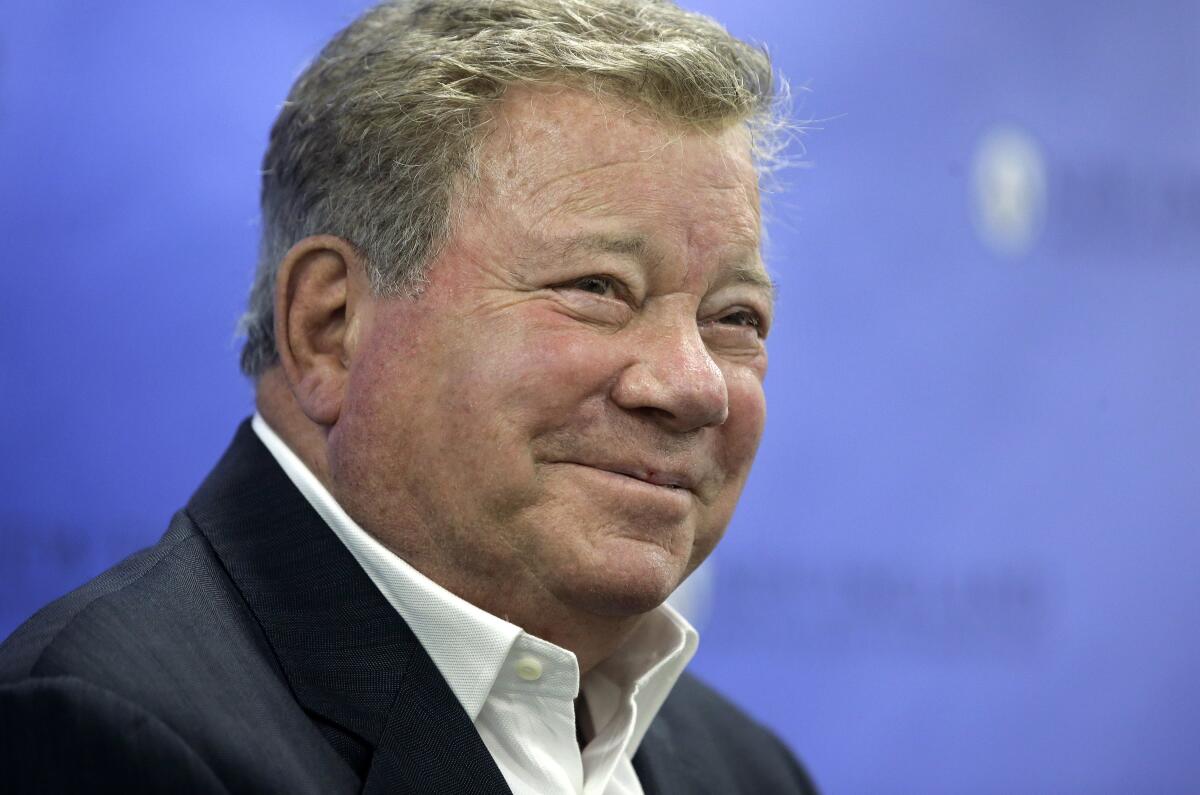 A man in a dark jacket and white shirt smiles for a camera