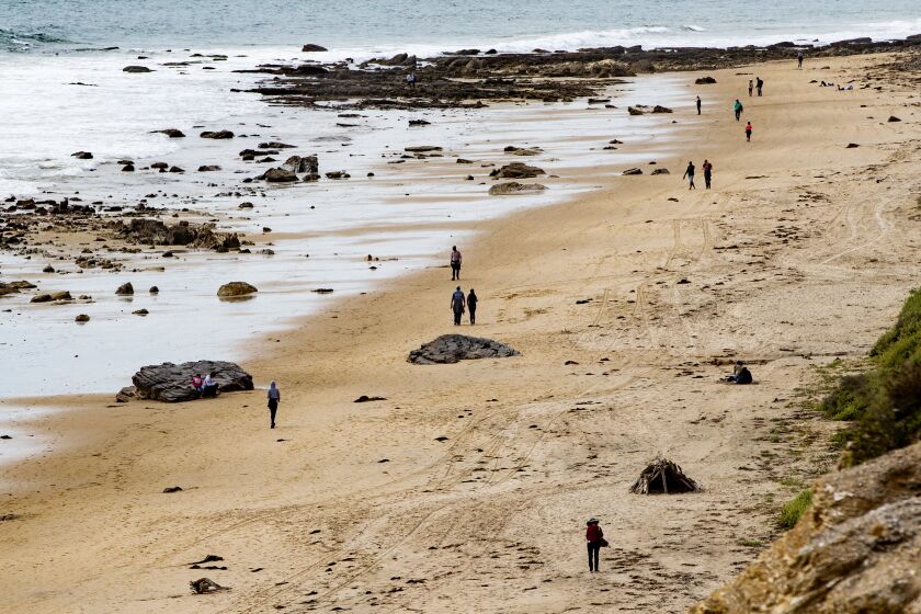 NEWPORT BEACH, CA - MARCH 20, 2020: People walk the beach, but maintain "social distancing" during the coronavirus outbreak at Crystal Cove on March 20, 2020 in Newport Beach, California. (Gina Ferazzi/Los AngelesTimes)