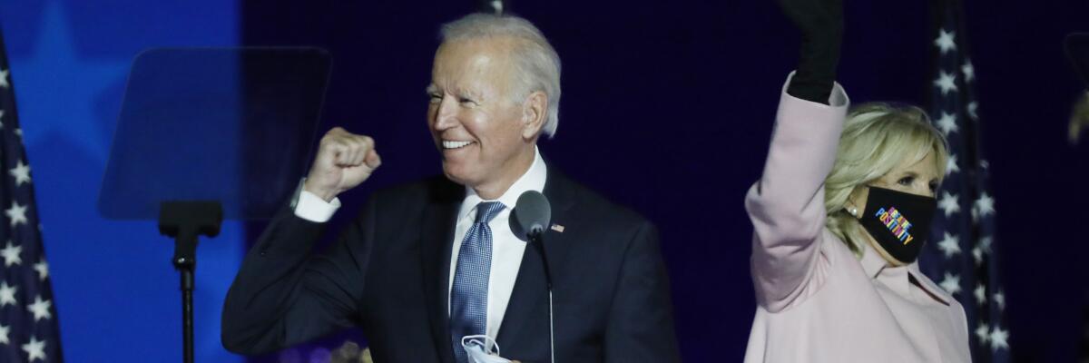 Democratic candidate Joe Biden, left, pumps his fist as his wife, Jill, waves her hand at a drive-in rally.