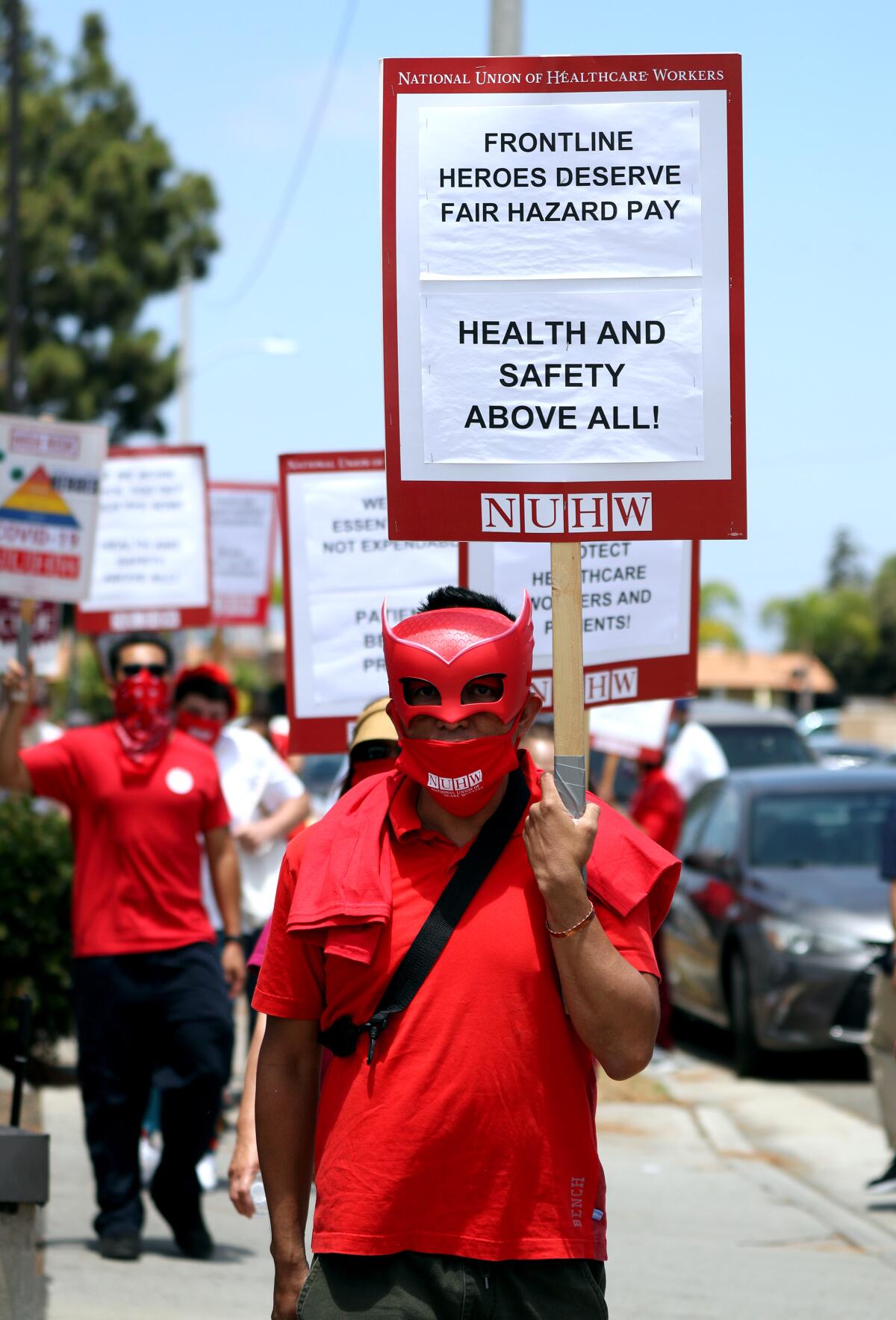 A protester at Kindred Hospital in Westminster wears a mask and a sign demanding fair hazard pay for frontline workers.