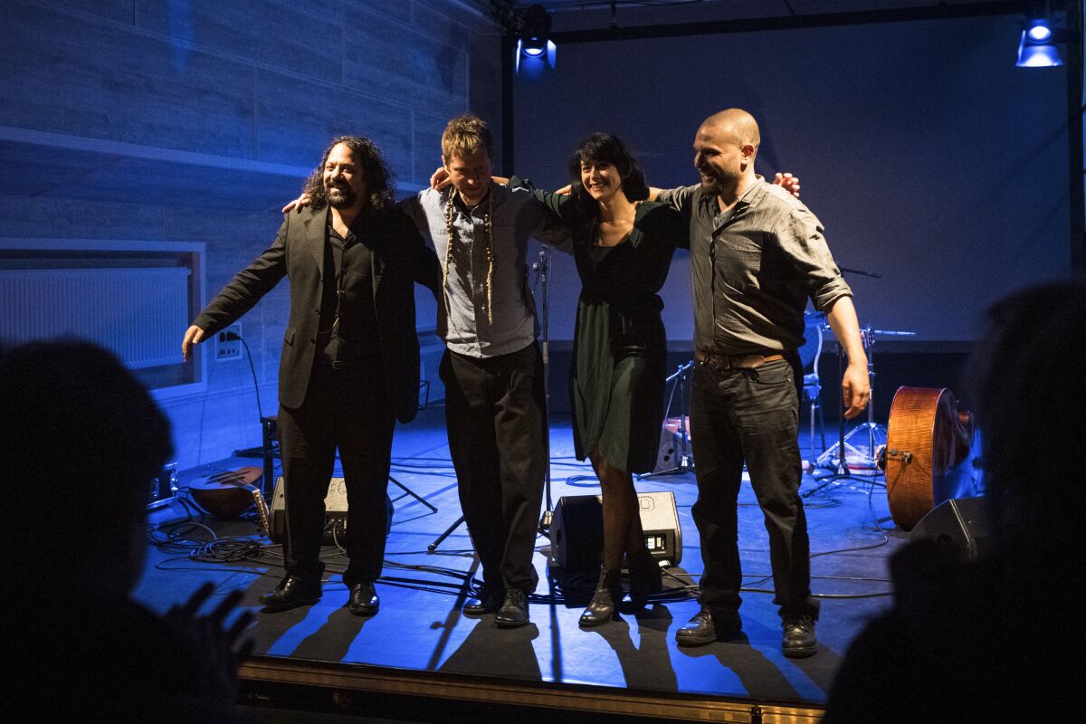 Wassim Mukdag, Borys Slowikowski, Eden Cami and Or Rozenfeld of Arab-Israeli-Jewish band Kayan Project acknowledge the applause of the audience during a concert at the Jewish theatre boat 'MS Goldberg' in Berlin, Sunday, May 29, 2022. The Berlin band Kayan Project, with a diverse cast of musicians from across the Middle East, might never been able to perform together in the members’ home countries. But it has risen to local fame in Berlin, Germany, with its unique style that combines oriental tunes with both Arabic and Hebrew lyrics. The band members include an Arab-Druze singer from northern Israel, a Syrian refugee and a Jewish Israeli bassist. (AP Photo/Stefanie Loos)