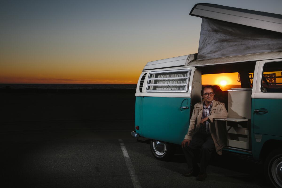 LA Times writer Gustavo Arellano poses for a portrait with his Volkswagen Bus at Dockweiler Beach Park on March 13 in El Segundo, California.