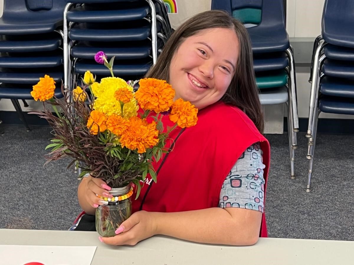 A STEP student displays a bouquet assembled as part of a "flower cart" activity that builds social and motor skills.