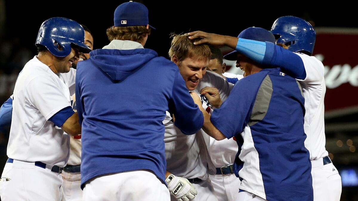 Dodgers catcher A.J. Ellis, center, is congratulated by his teammates after driving in the winning run on a sacrifice fly in the ninth inning of a 1-0 victory over the San Diego Padres on Saturday.