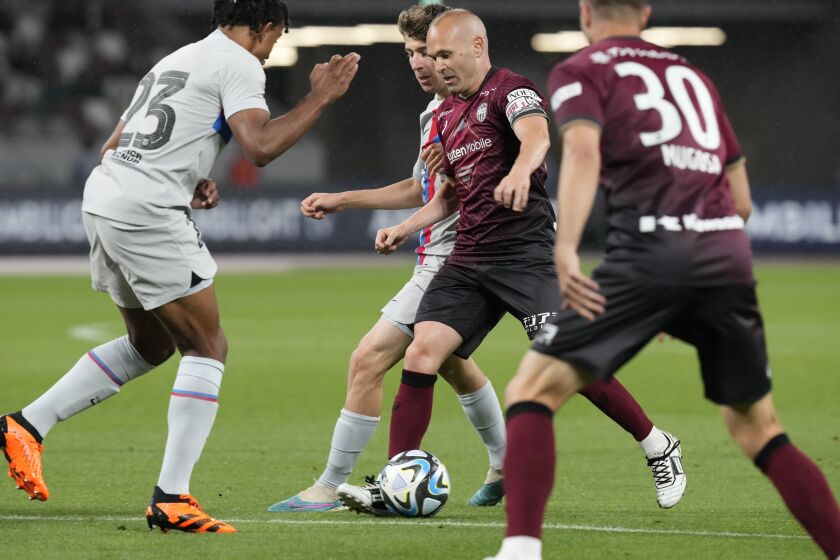 Vissel Kobe's Andres Iniesta, center, takes control of the ball during a friendly soccer match between his Japanese club Vissel Kobe and his old club Barcelona at the National Stadium in Tokyo, Tuesday, June 6, 2023. (AP Photo/Eugene Hoshiko)