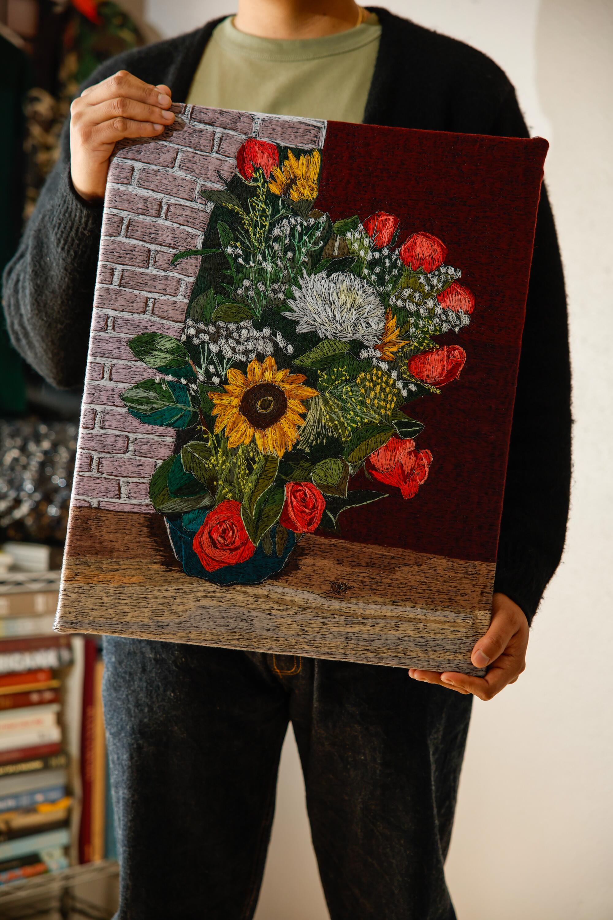 Artist Erick Medel holds one of his textile art pieces 