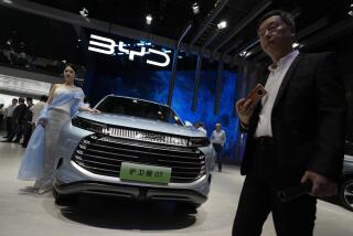 FILE - A model stands next to a car from BYD during the Shanghai auto show in Shanghai, on April 18, 2023. BYD Co., based in the southern China tech hub of Shenzhen, dethroned Texas-based Tesla Inc. as the top seller of electric cars in the last three months of 2023, according to sales figures released by the companies this week. (AP Photo/Ng Han Guan, File)