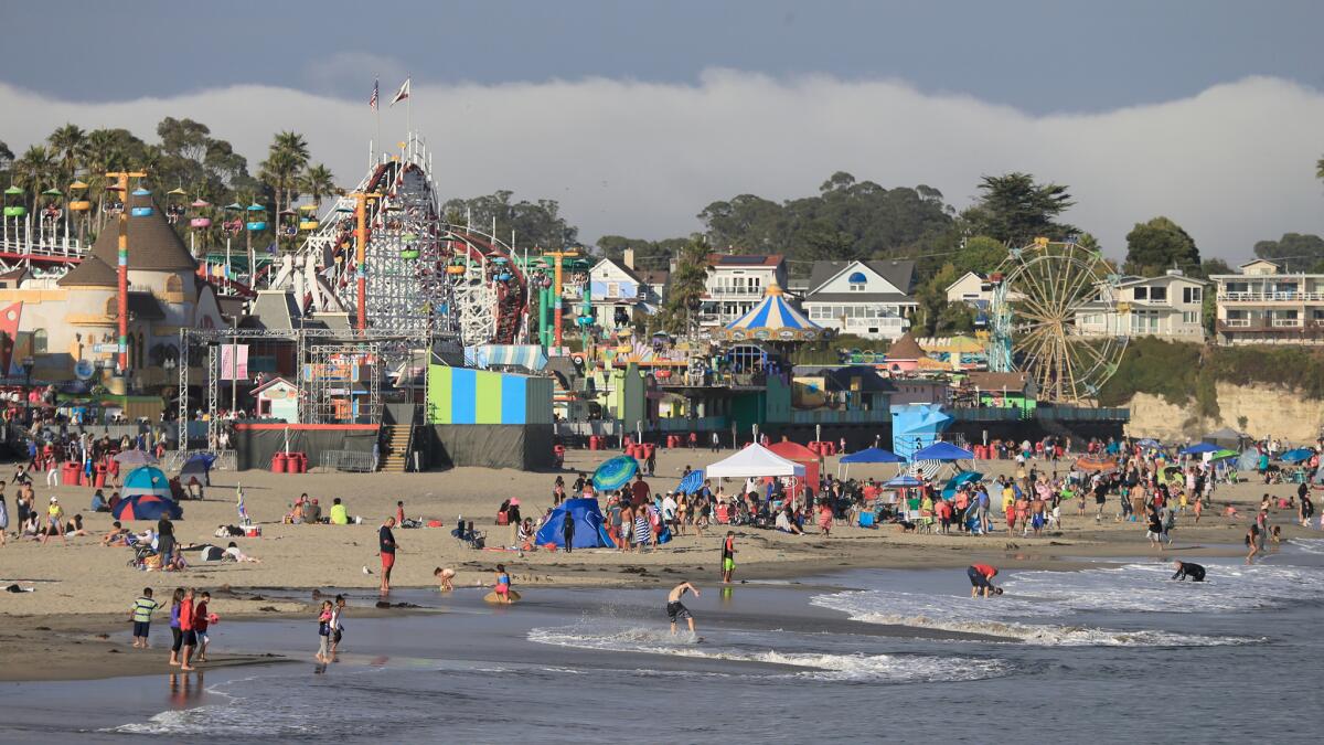 People fill the beach near the Santa Cruz Beach Boardwalk amusement park.