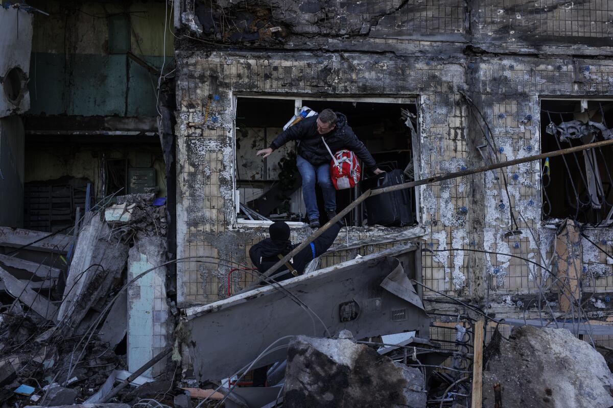 A person leaves through a window of a heavily damaged building.